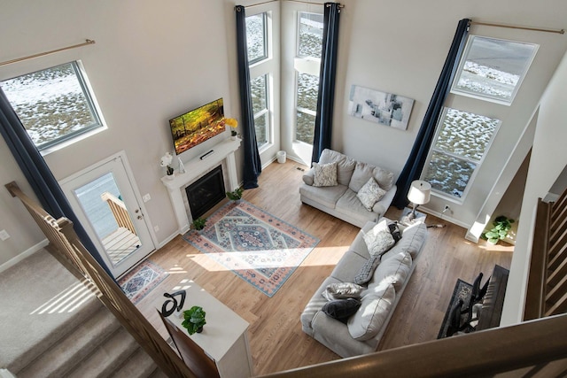 living room featuring a towering ceiling, a wealth of natural light, and light wood-type flooring