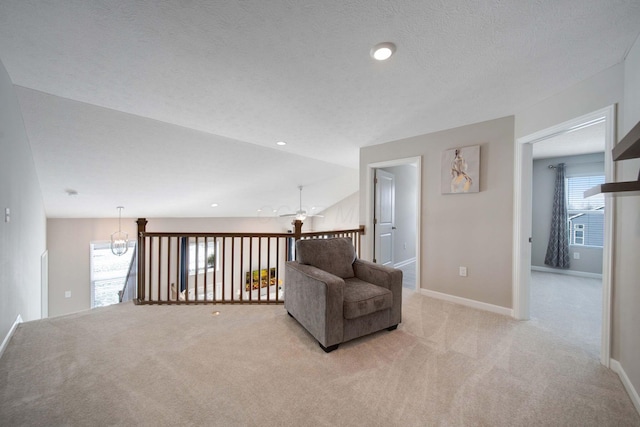 living area with ceiling fan, light colored carpet, lofted ceiling, and a textured ceiling