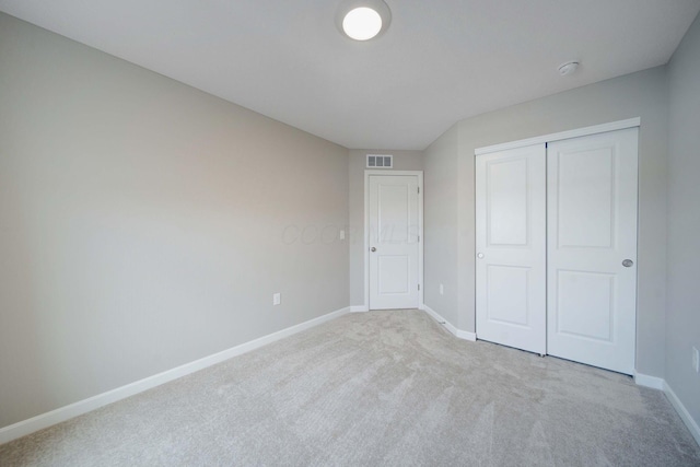 unfurnished bedroom with light colored carpet and a closet