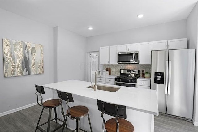 kitchen featuring sink, stainless steel appliances, a kitchen island with sink, decorative backsplash, and white cabinets