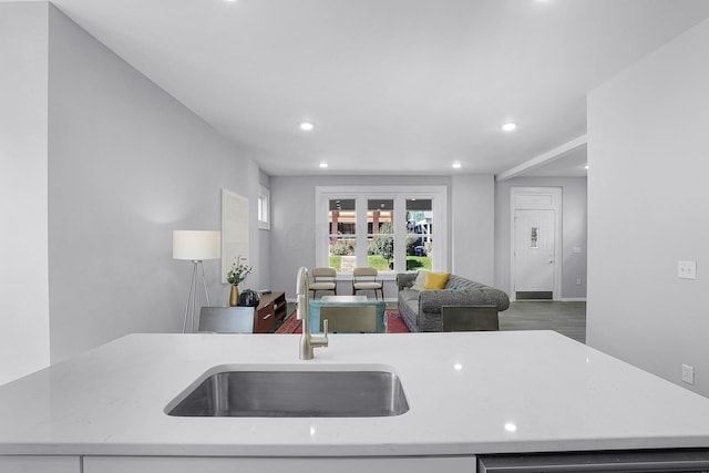 kitchen featuring sink, dishwashing machine, and light stone counters