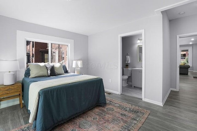 bedroom with ensuite bathroom and dark hardwood / wood-style flooring