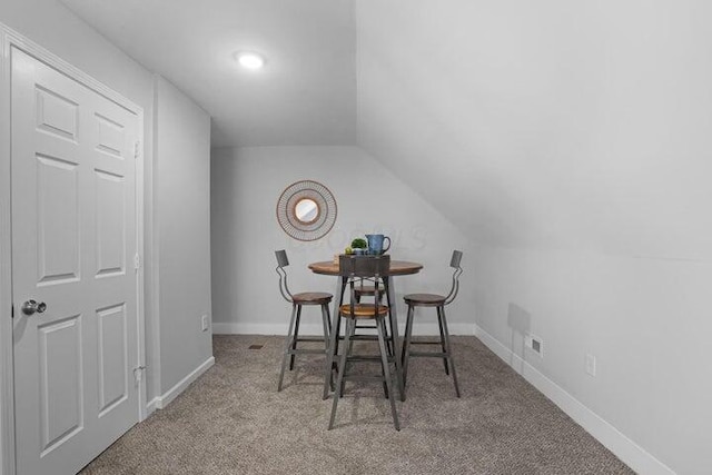 dining area featuring light colored carpet and lofted ceiling