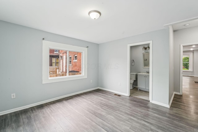 392 Morrison Ave, Columbus, OH 43205 - unfurnished bedroom with wood finished floors, baseboards, and ensuite bath