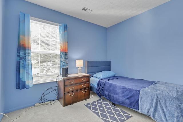 bedroom featuring light colored carpet and a textured ceiling