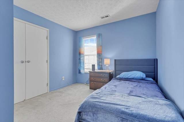 bedroom with light colored carpet, a closet, and a textured ceiling