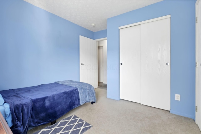 bedroom with carpet floors, a textured ceiling, and a closet