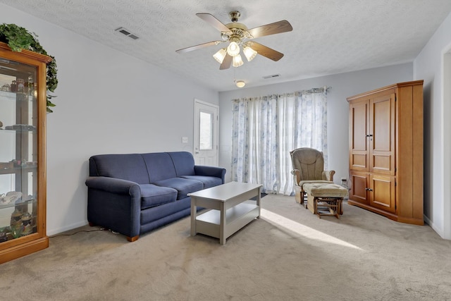 carpeted living room featuring ceiling fan and a textured ceiling