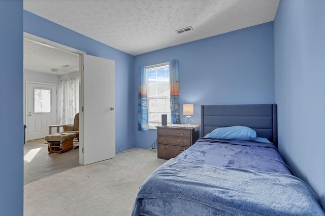 carpeted bedroom featuring multiple windows and a textured ceiling