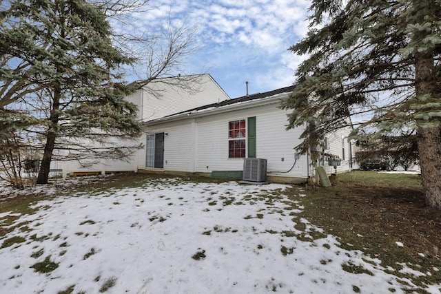 snow covered rear of property featuring central air condition unit