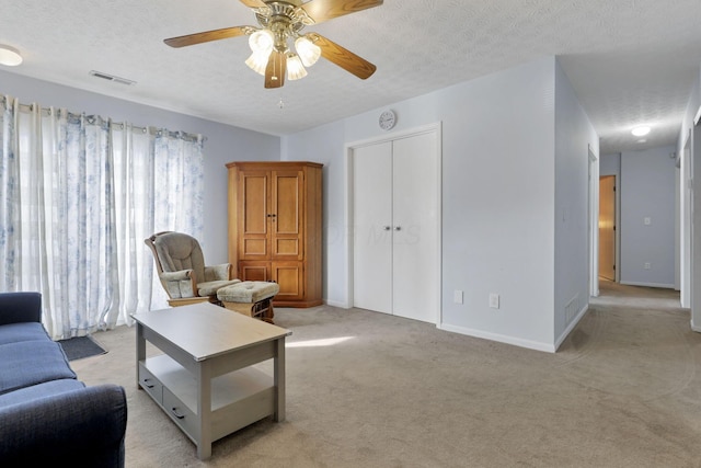 carpeted living room with ceiling fan and a textured ceiling