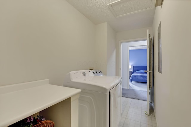 clothes washing area with independent washer and dryer and a textured ceiling