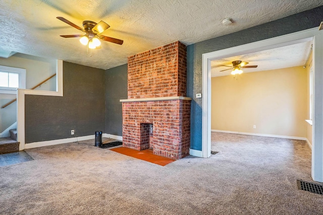 unfurnished living room featuring ceiling fan, carpet floors, a brick fireplace, and a textured ceiling