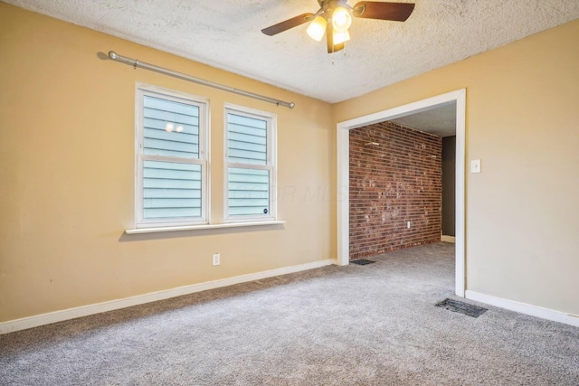 carpeted empty room featuring ceiling fan, a textured ceiling, and brick wall