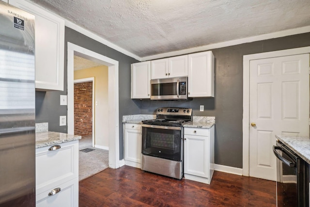 kitchen featuring dark wood-type flooring, white cabinetry, light stone counters, a textured ceiling, and appliances with stainless steel finishes