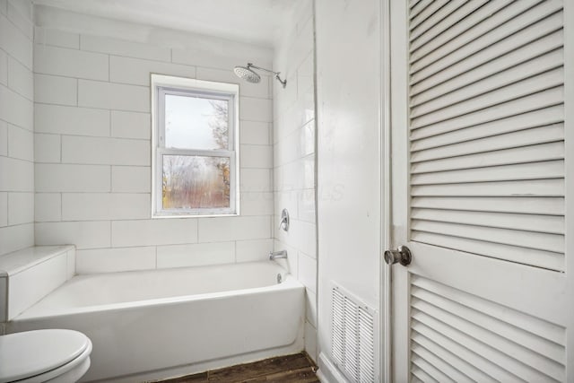 bathroom with tiled shower / bath, wood-type flooring, and toilet