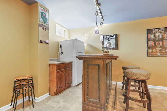 bar with hanging light fixtures and white fridge