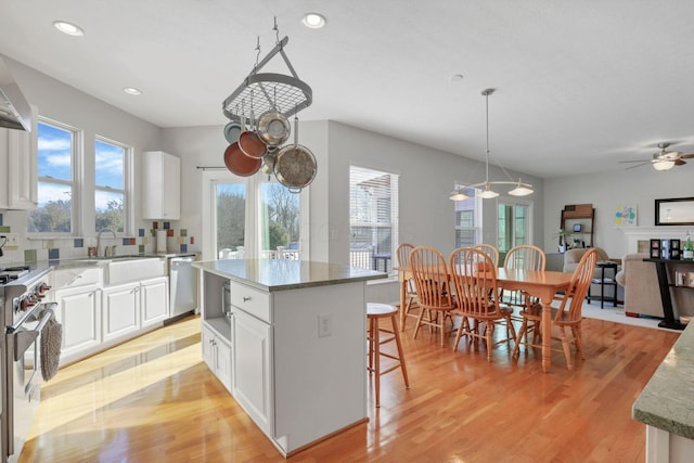 kitchen featuring appliances with stainless steel finishes, pendant lighting, white cabinetry, sink, and a center island