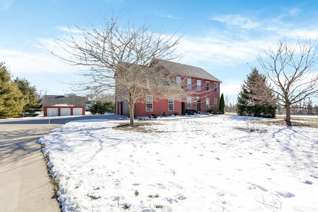 snow covered property featuring a garage and an outdoor structure