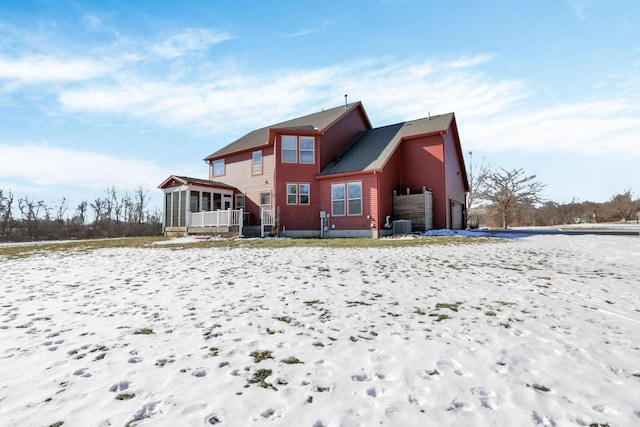 snow covered rear of property featuring a sunroom and central air condition unit