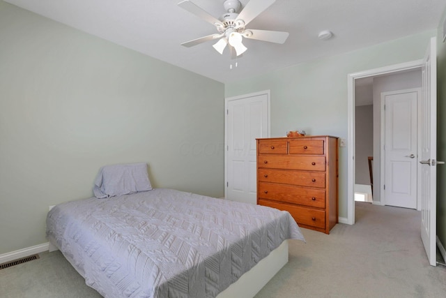 bedroom with light colored carpet, ceiling fan, and a closet