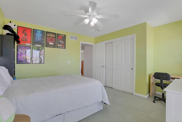 bedroom featuring light colored carpet, ceiling fan, and a closet