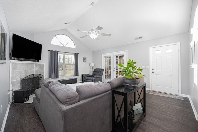 living room with a tile fireplace, vaulted ceiling, dark hardwood / wood-style flooring, ceiling fan, and french doors