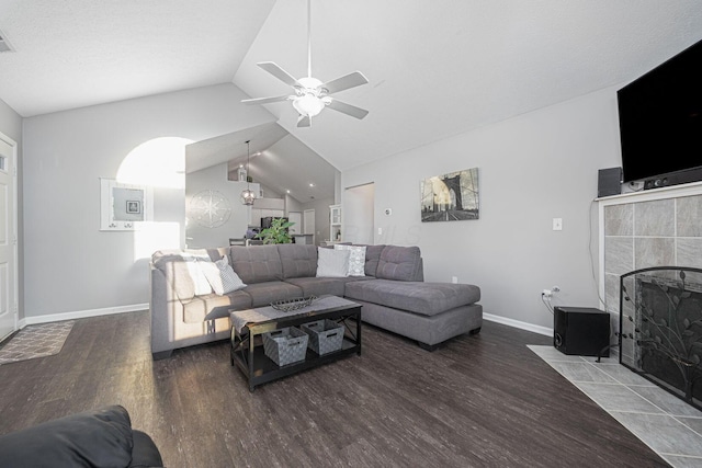 living room featuring a tiled fireplace, vaulted ceiling, ceiling fan, and dark hardwood / wood-style flooring