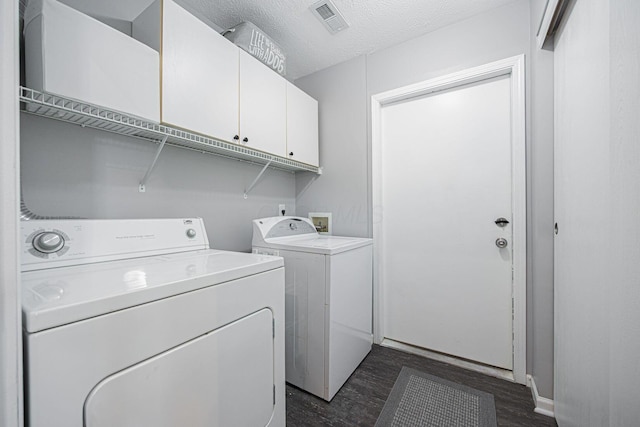 clothes washing area with cabinets, dark hardwood / wood-style flooring, washer and dryer, and a textured ceiling