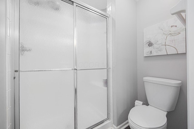 bathroom with a shower with shower door and toilet