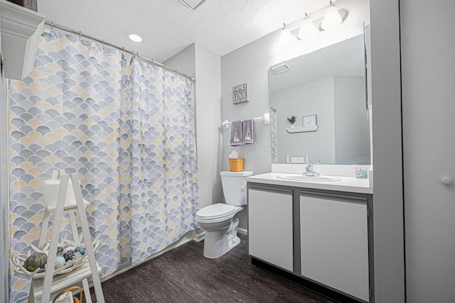 bathroom featuring vanity, wood-type flooring, toilet, and a textured ceiling