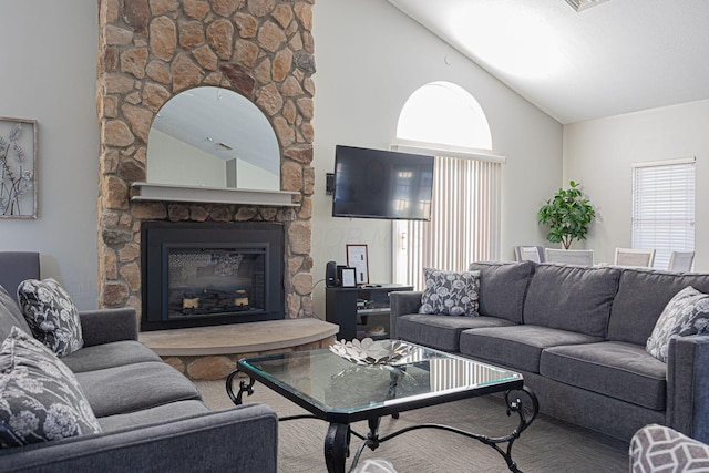 living room featuring a stone fireplace, vaulted ceiling, and a healthy amount of sunlight