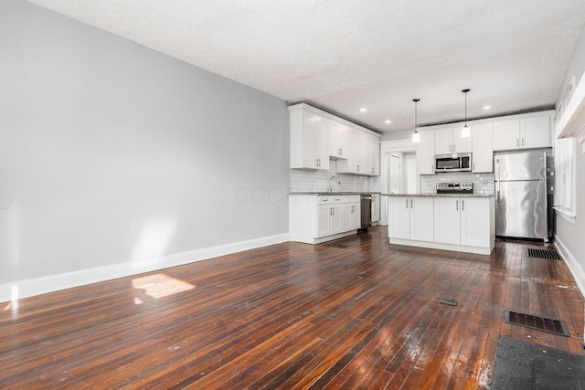 kitchen featuring stainless steel appliances, white cabinetry, a kitchen island, and pendant lighting