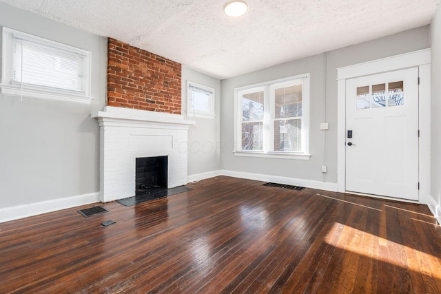 unfurnished living room with dark hardwood / wood-style floors, a fireplace, and a textured ceiling