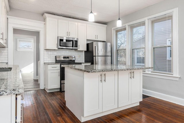 kitchen with white cabinetry, hanging light fixtures, tasteful backsplash, and stainless steel appliances