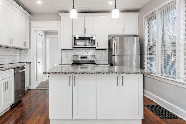 kitchen with a kitchen island, white cabinetry, appliances with stainless steel finishes, and decorative light fixtures