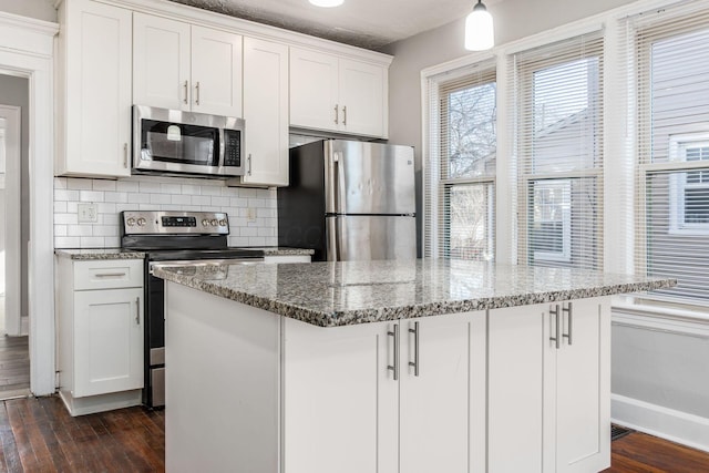 kitchen with white cabinetry, appliances with stainless steel finishes, dark hardwood / wood-style flooring, a kitchen island, and decorative backsplash