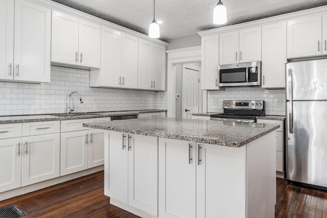 kitchen with sink, white cabinetry, hanging light fixtures, stainless steel appliances, and a center island