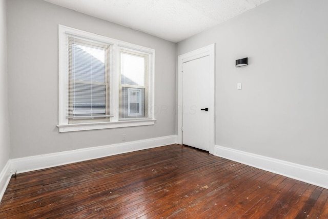 spare room featuring dark hardwood / wood-style floors and a textured ceiling