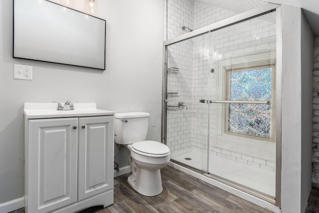 bathroom with vanity, hardwood / wood-style flooring, a shower with shower door, and toilet