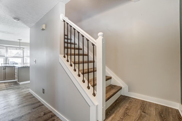 stairway with hardwood / wood-style floors and a textured ceiling