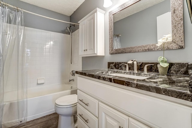 full bathroom featuring hardwood / wood-style floors, vanity, shower / bath combination with curtain, a textured ceiling, and toilet