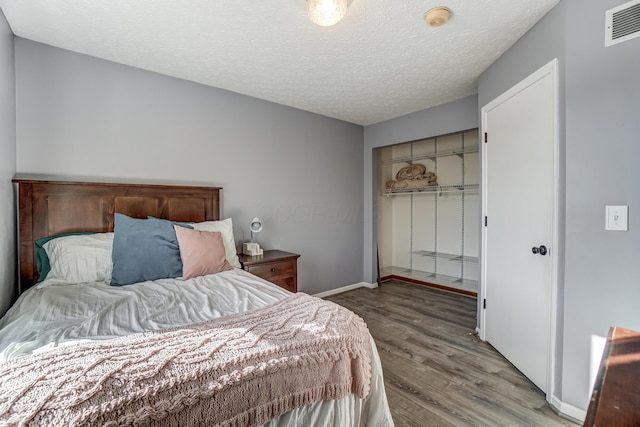 bedroom featuring a closet, wood-type flooring, and a textured ceiling