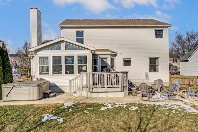 back of property with a hot tub, a lawn, a patio area, and an outdoor fire pit