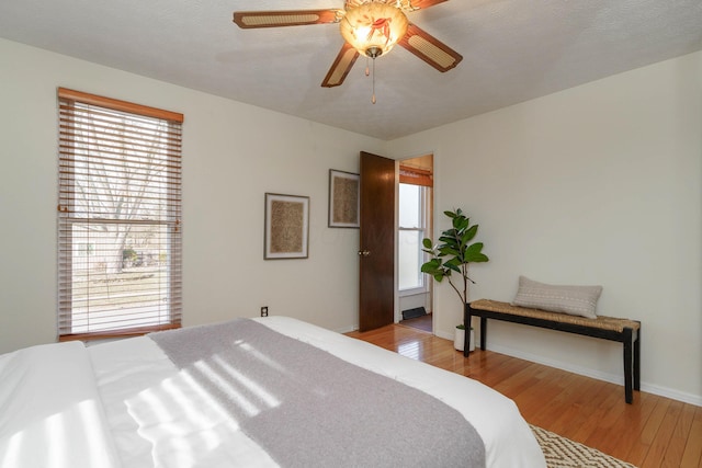 bedroom with multiple windows, ceiling fan, and light wood-type flooring