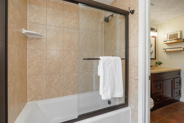 full bathroom with bath / shower combo with glass door, vanity, toilet, tile patterned floors, and a textured ceiling