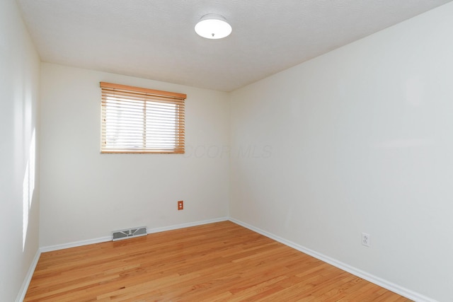 empty room with a textured ceiling and light wood-type flooring