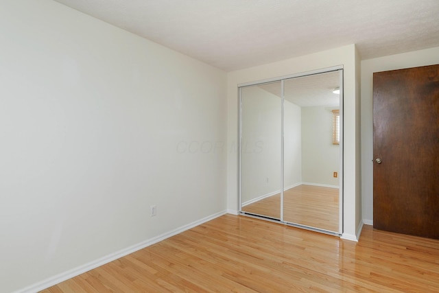 unfurnished bedroom featuring a closet, light hardwood / wood-style flooring, and a textured ceiling