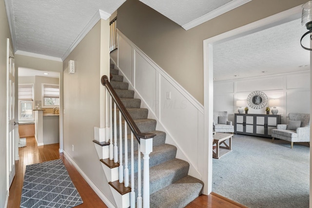 stairway featuring ornamental molding, wood-type flooring, sink, and a textured ceiling