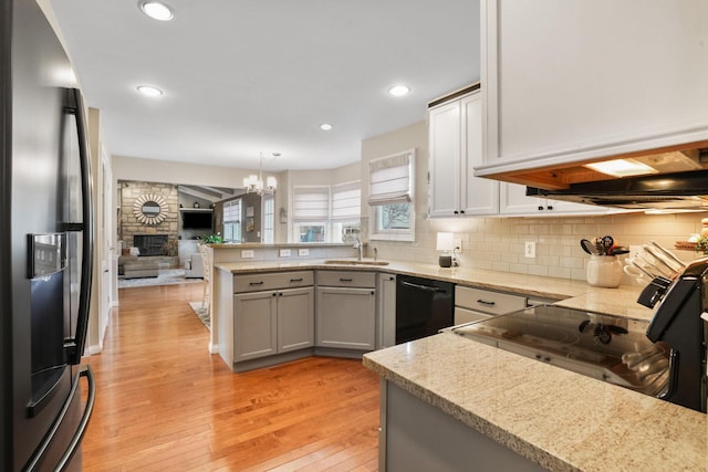 kitchen with sink, hanging light fixtures, tasteful backsplash, black appliances, and kitchen peninsula